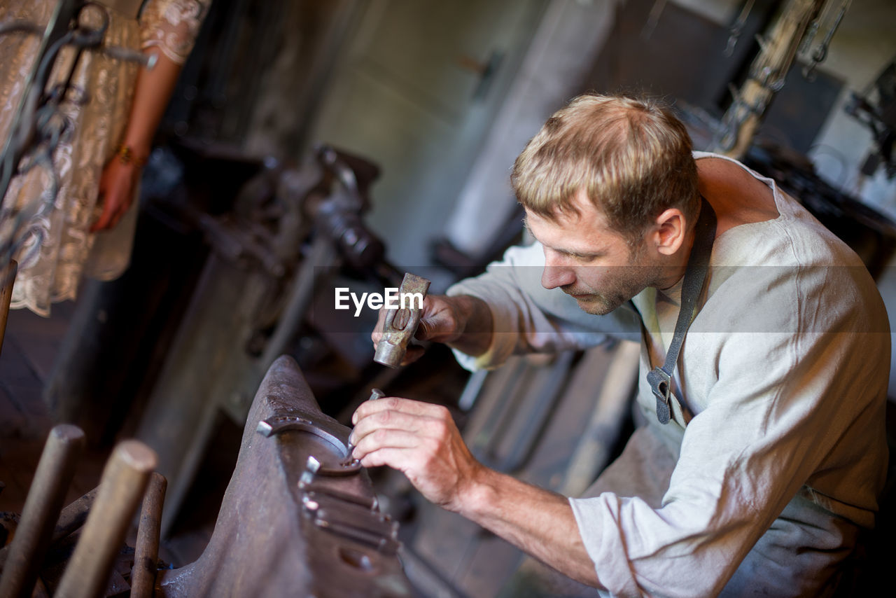 Full length of man making horseshoe in workshop