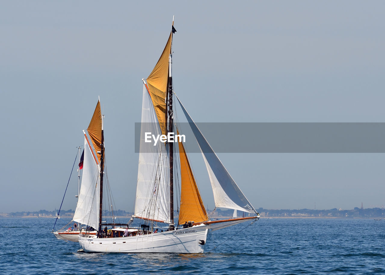 SAILBOATS SAILING ON SEA AGAINST CLEAR SKY