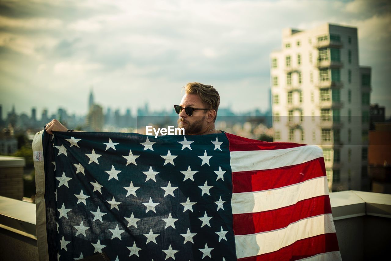 Portrait of man with american flag standing in city