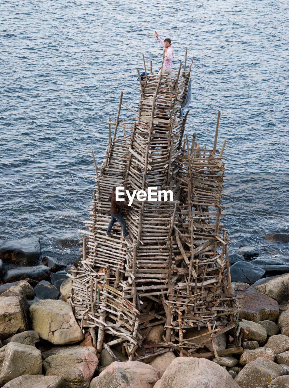 High angle view of friends climbing on built structure against sea