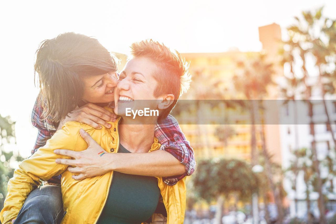 Smiling lesbian couple against buildings