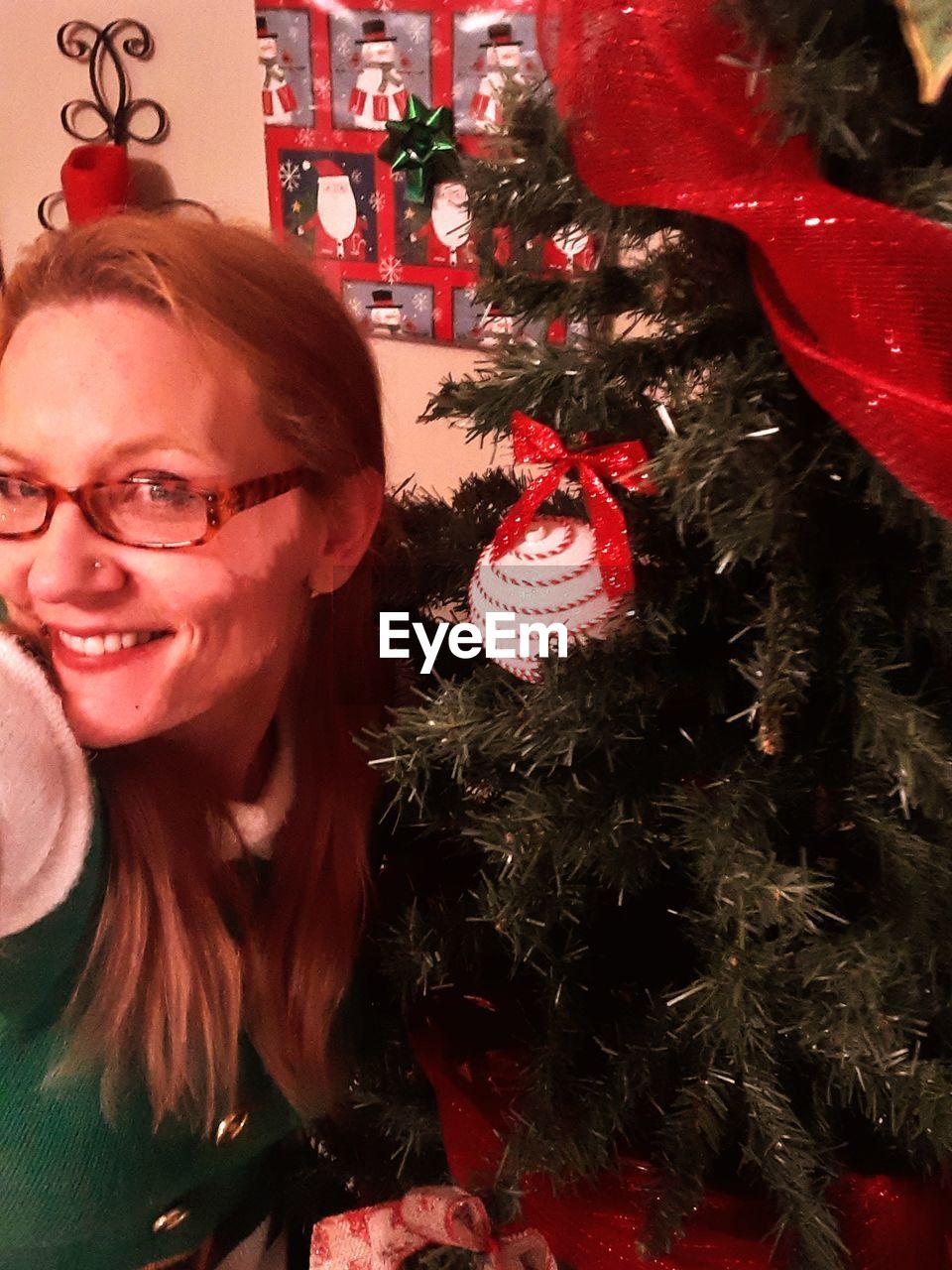 PORTRAIT OF SMILING YOUNG WOMAN WITH CHRISTMAS TREE