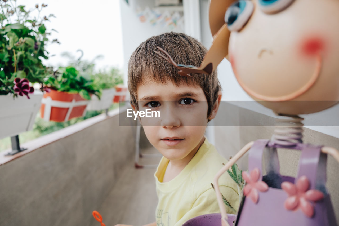 Portrait of boy by toy in balcony