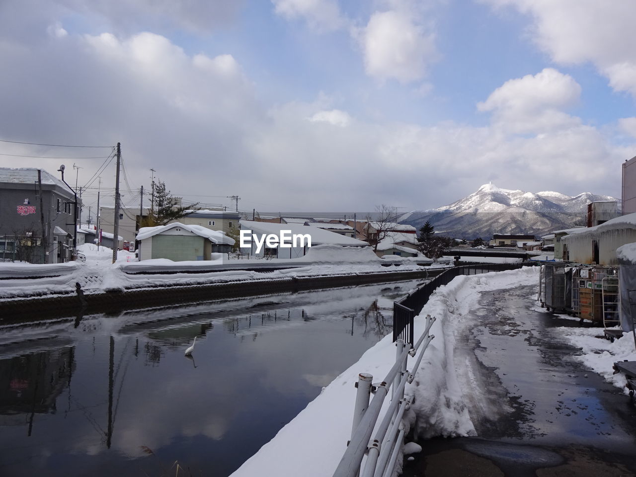 Panoramic view of frozen river by buildings against sky