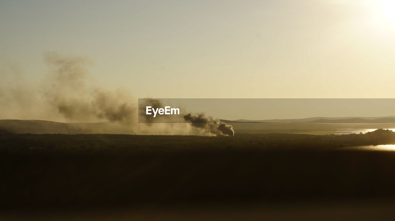 Steam emitting from volcanic landscape against clear sky during sunset