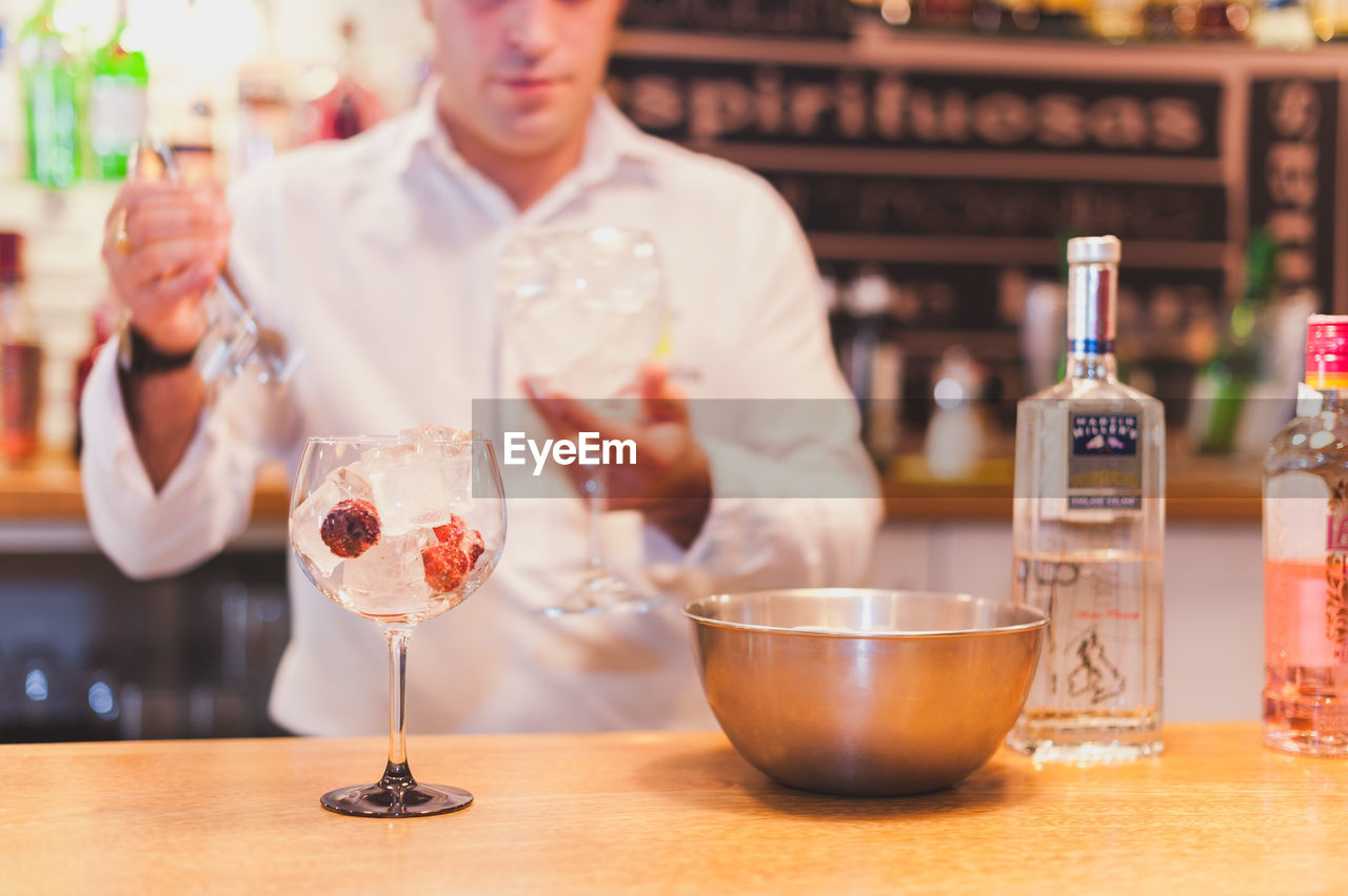 Midsection of bartender preparing drink at counter