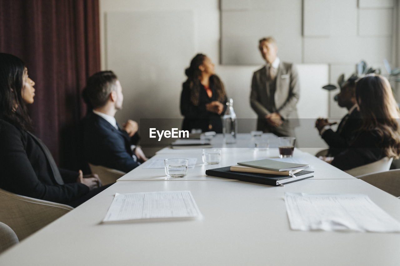 Documents and diaries at desk with business colleagues during meeting in office