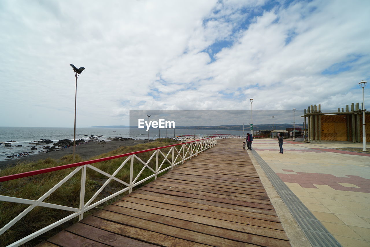 PEOPLE ON PIER OVER SEA AGAINST SKY