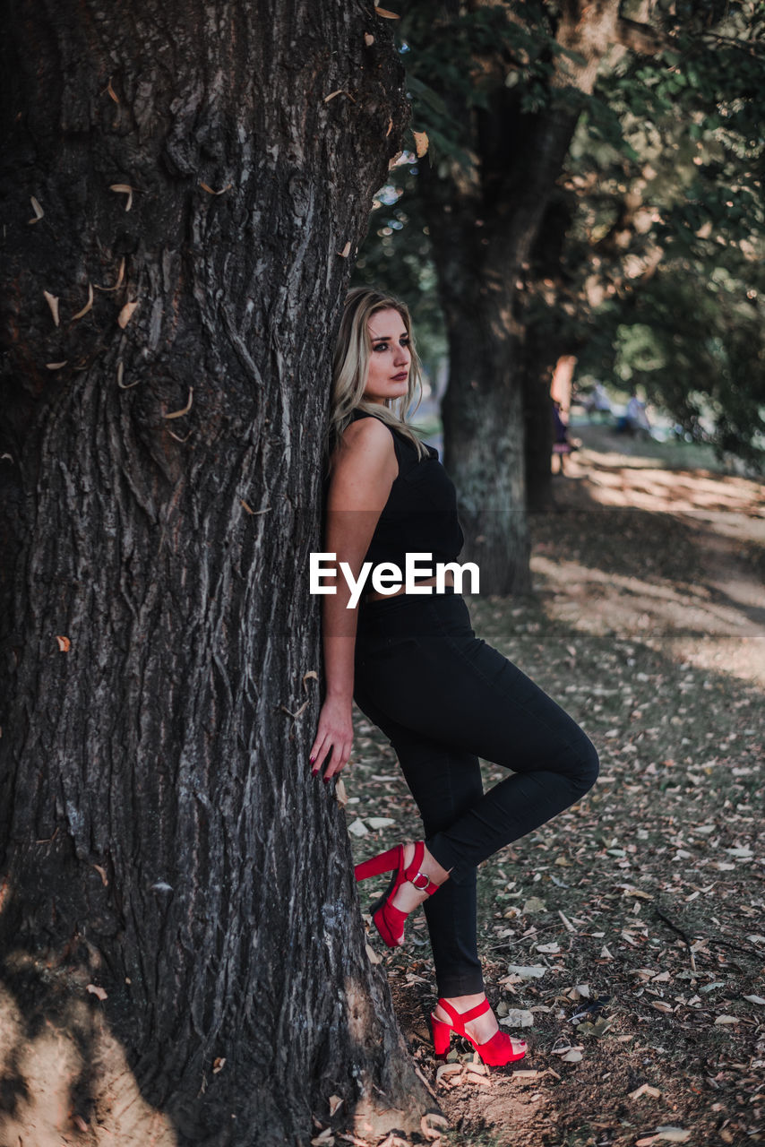 Woman leaning on tree in forest