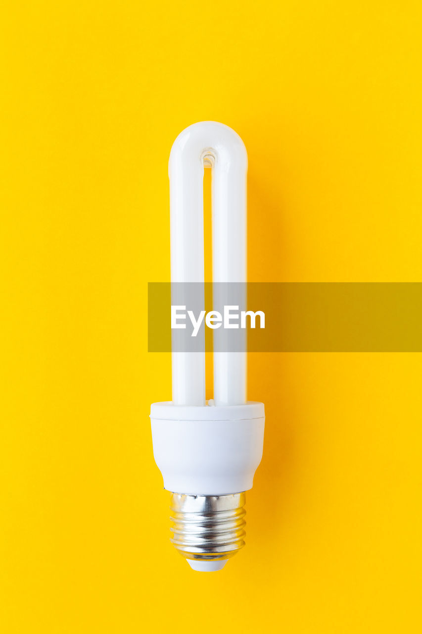 Close-up of light bulb against yellow background