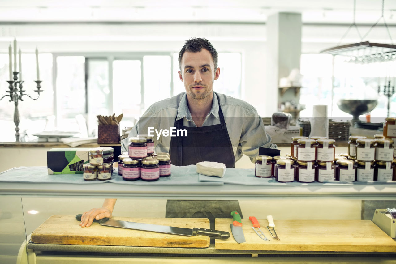 Portrait of mid adult salesman at supermarket counter