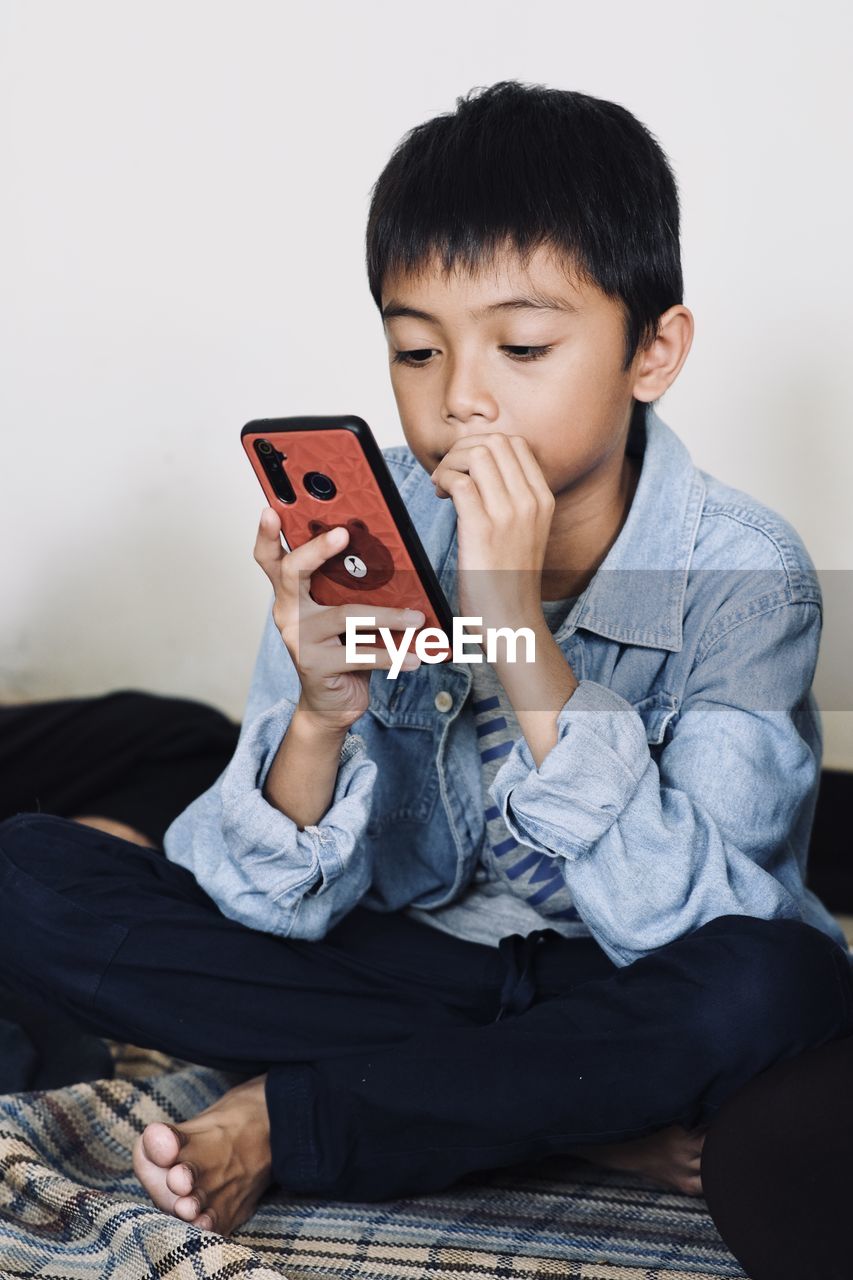 Young man using mobile phone while sitting on sofa at home