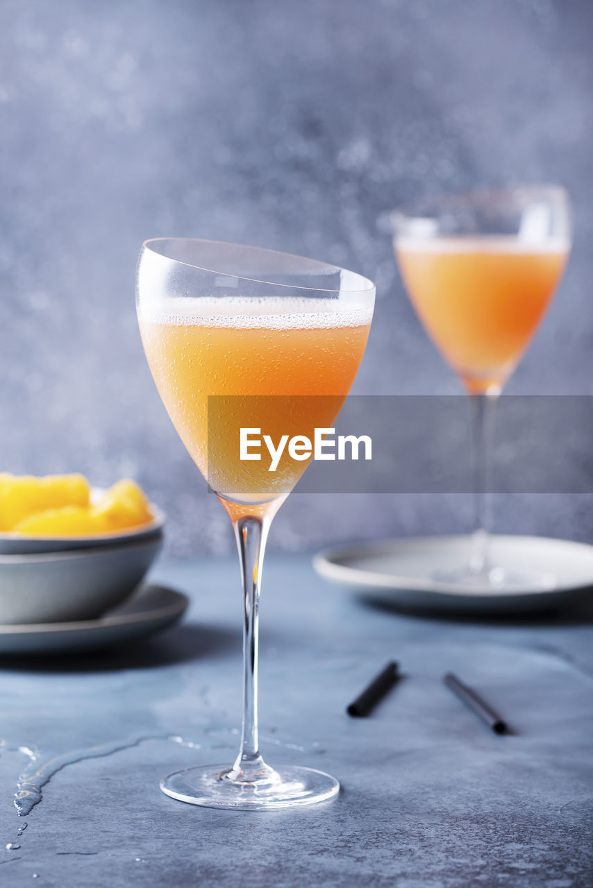 CLOSE-UP OF WINEGLASS ON TABLE WITH GLASS OF JUICE