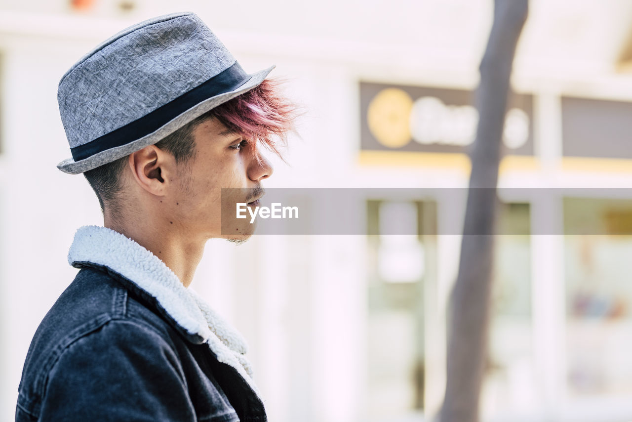 PORTRAIT OF MAN WEARING HAT LOOKING AWAY OUTDOORS