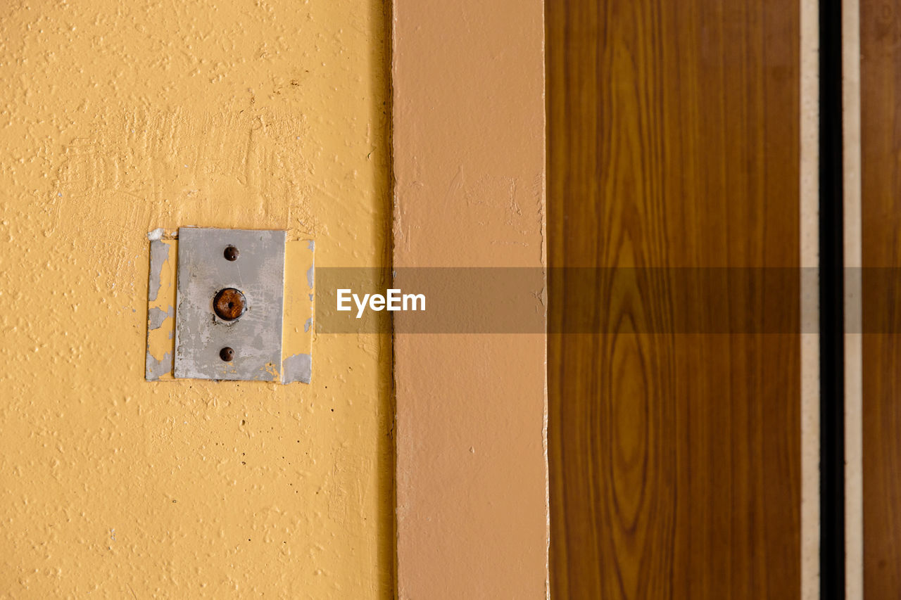 door, wood, entrance, wall, no people, wall - building feature, floor, security, protection, yellow, built structure, architecture, close-up, light switch, electricity, metal, full frame, keyhole, lock, day, closed, building exterior