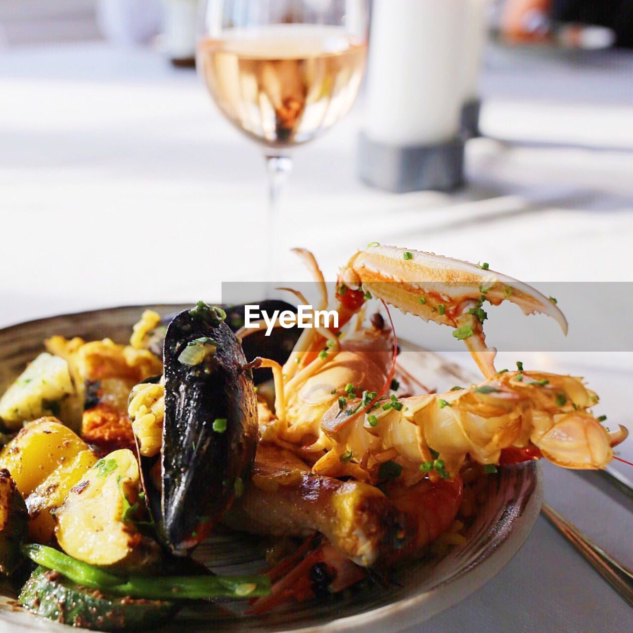 Close-up of paella served with white wine on table in restaurant