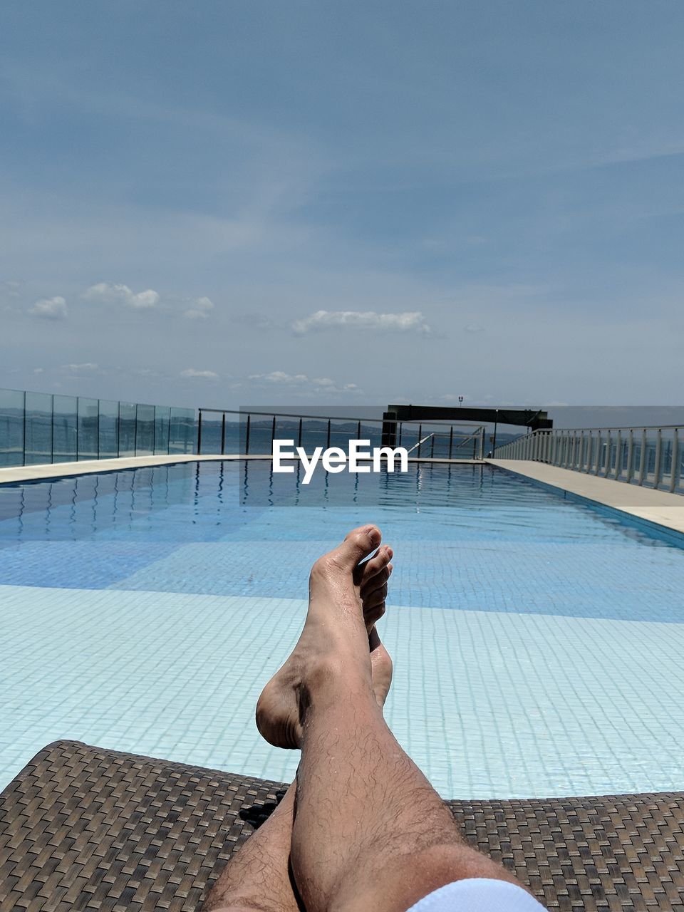 Low section of man in swimming pool against sky