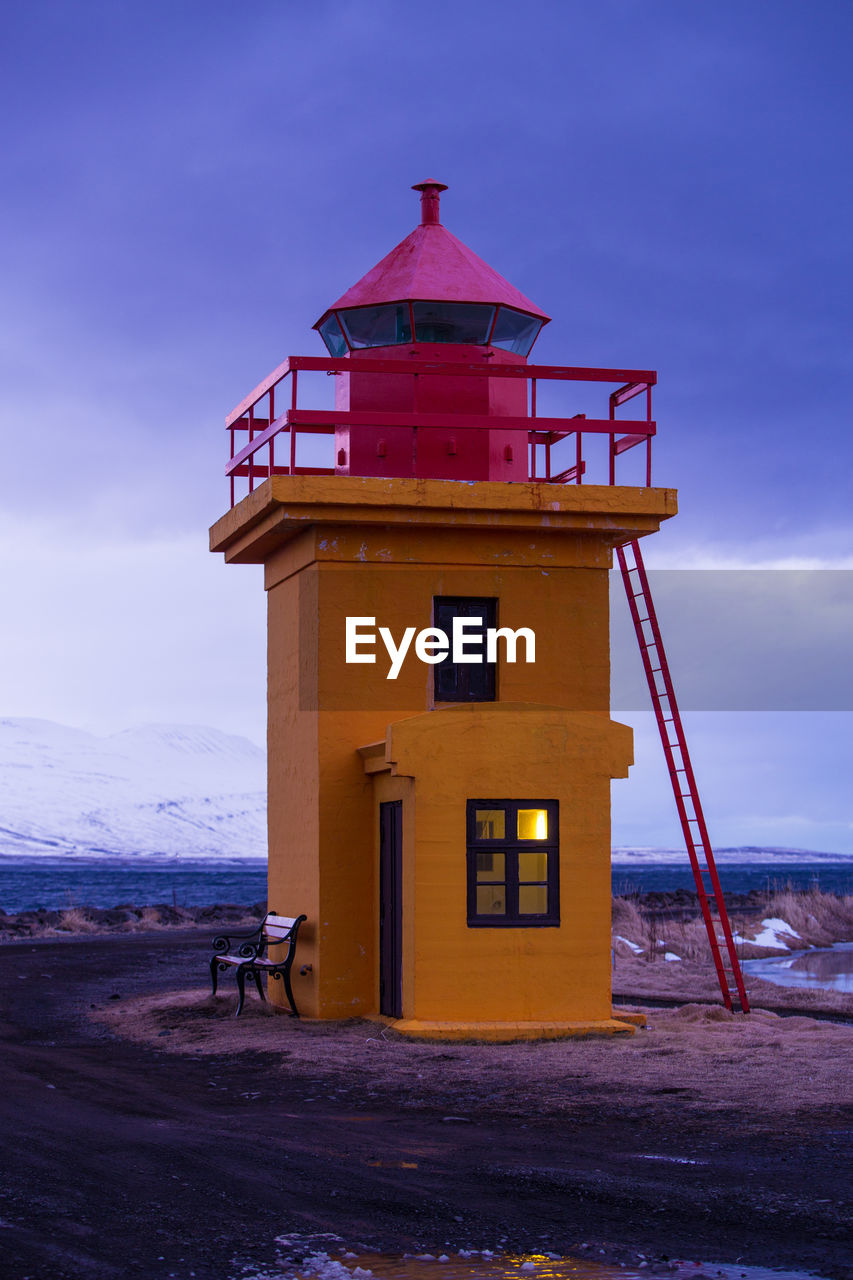 Orange lighthouse at the ocean in the evening, iceland