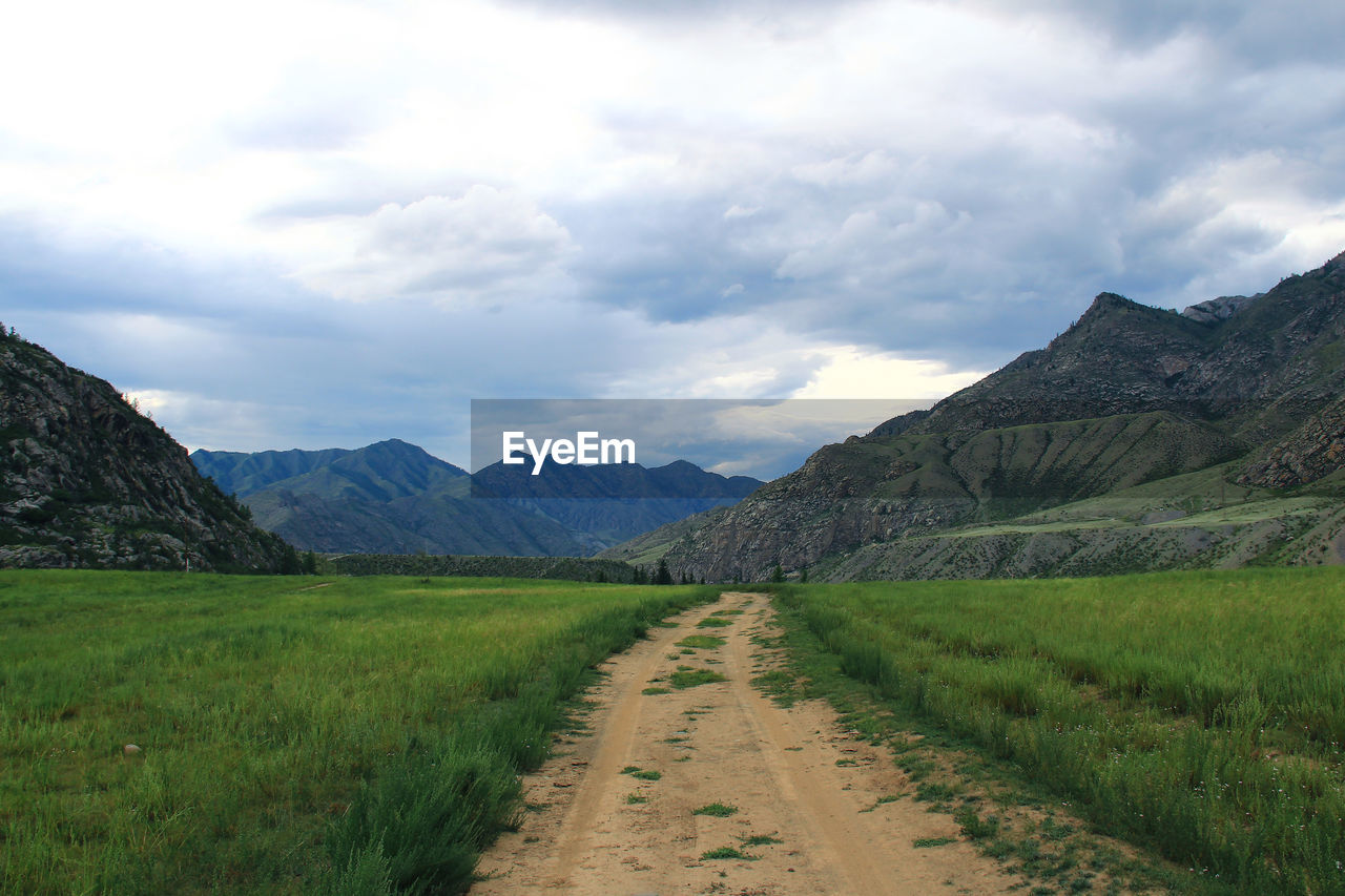 The road in a wide alpine gorge in altai against the background of high mountain ranges in summer