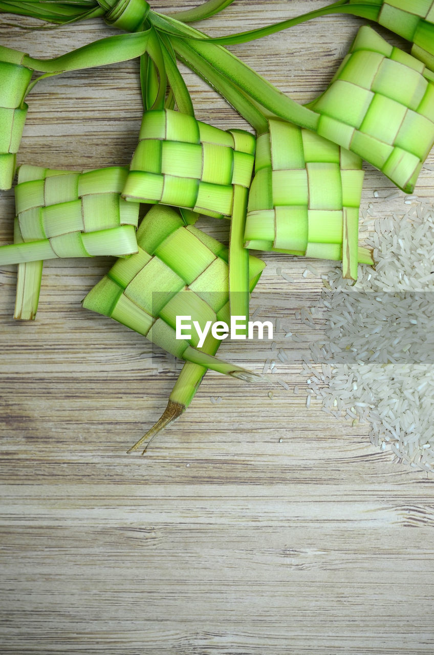 Handmade ketupat or dumpling rice for hari raya aidilfitri with uncooked rice on wooden background