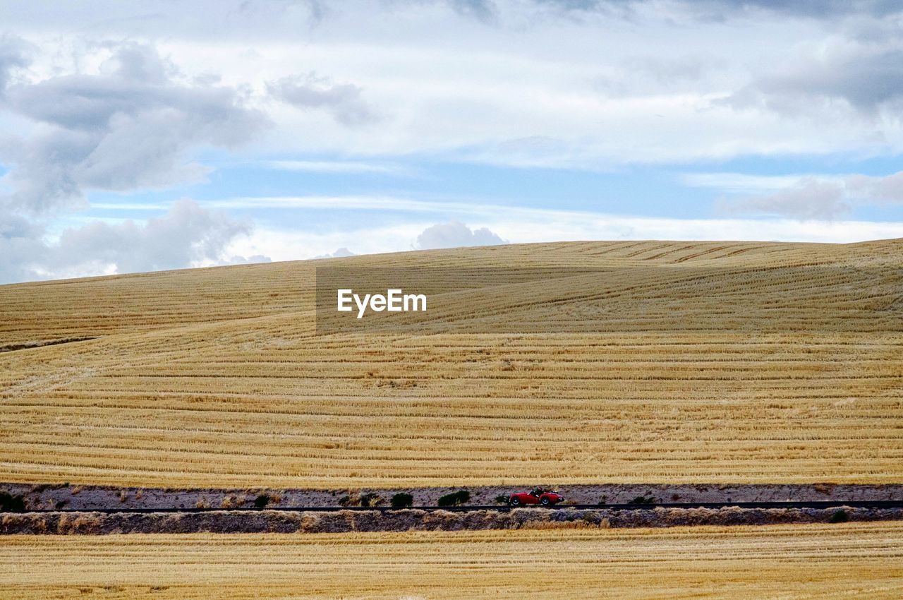 View of harvested rolling landscape against cloudy sky