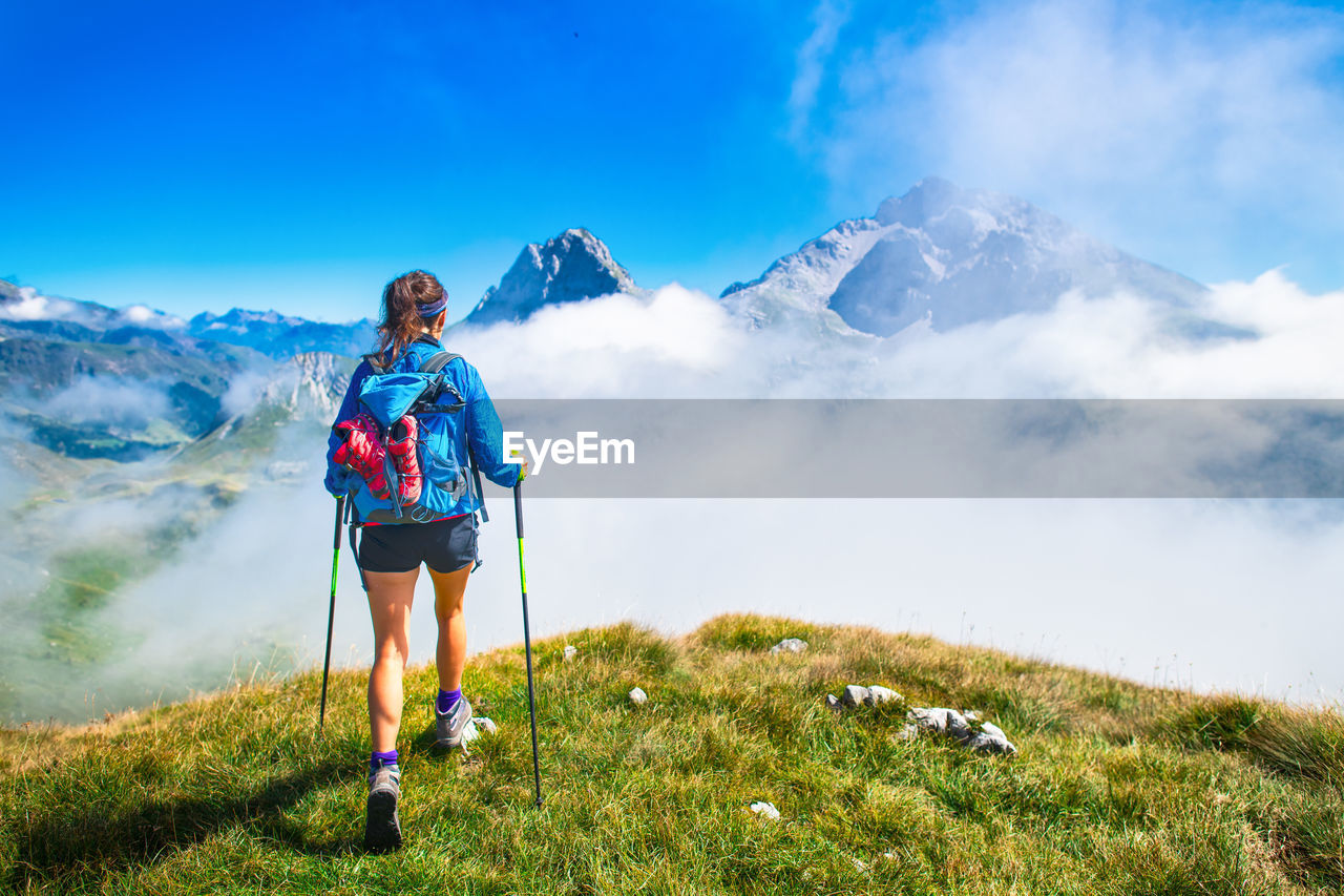 FULL LENGTH OF WOMAN STANDING ON MOUNTAIN AGAINST SKY