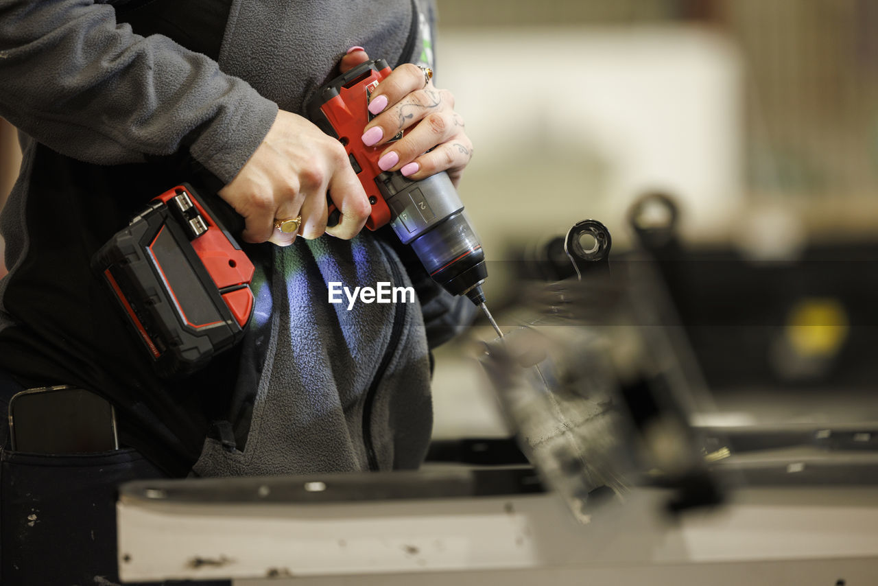 Woman using drilling machine in factory