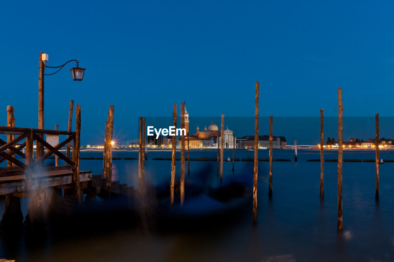 Wooden posts in grand canal at night