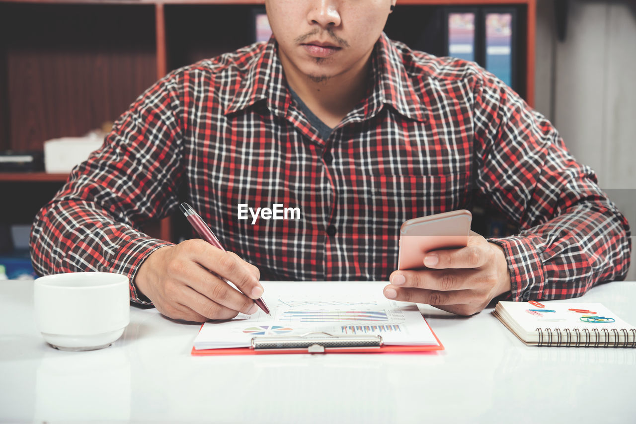 MIDSECTION OF MAN SITTING ON TABLE