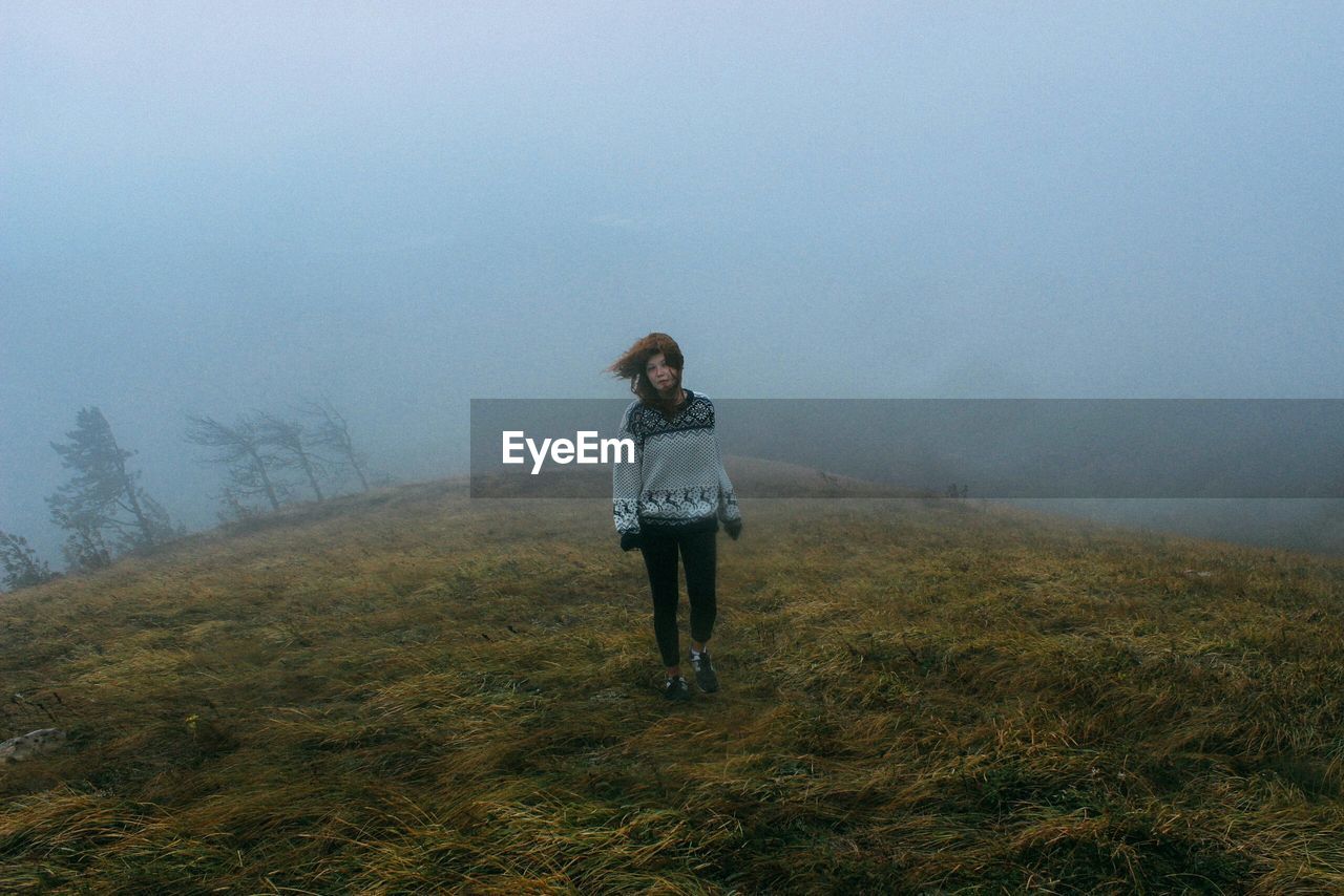 Full length of woman walking on field during foggy weather