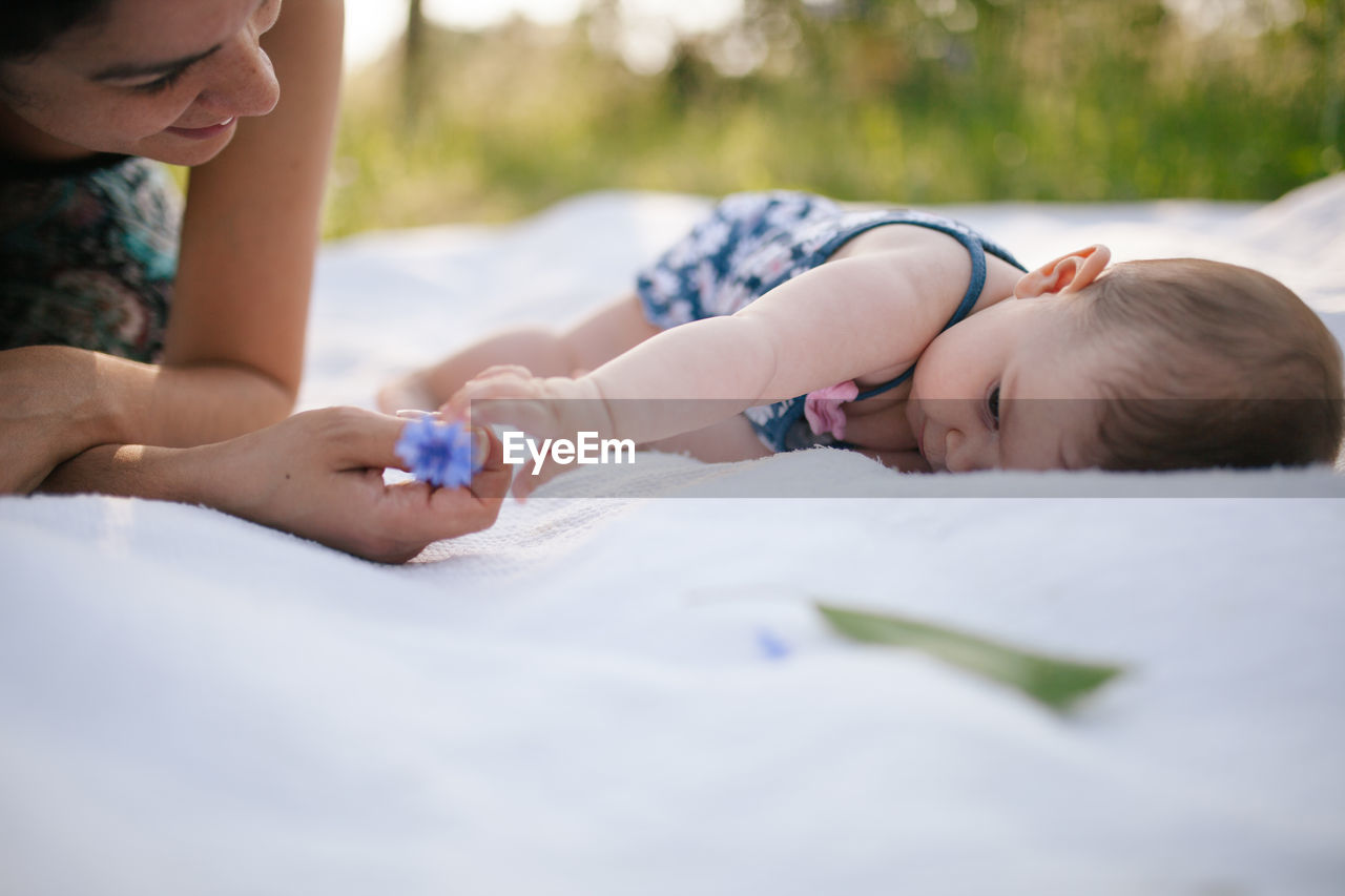 Mother playing with daughter on picnic blanket