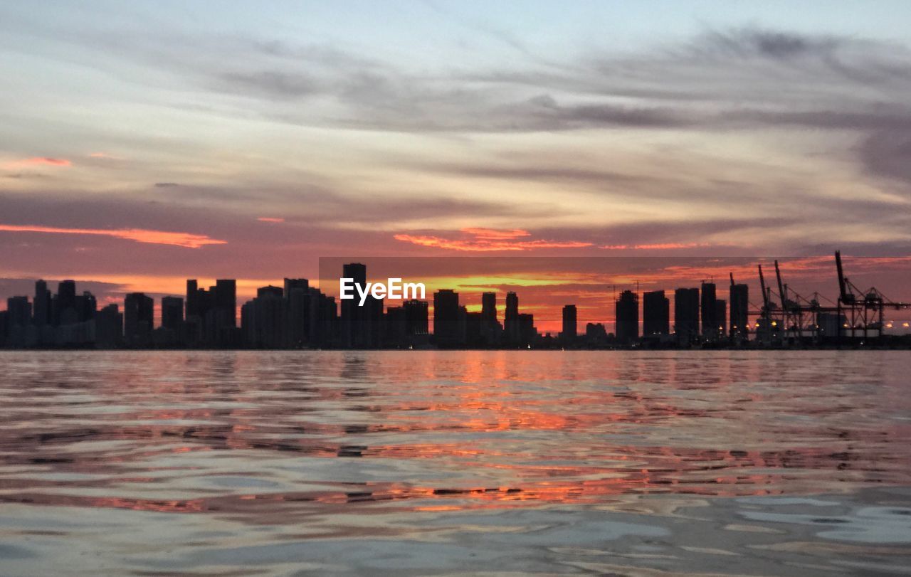 SEA AND BUILDINGS IN CITY DURING SUNSET