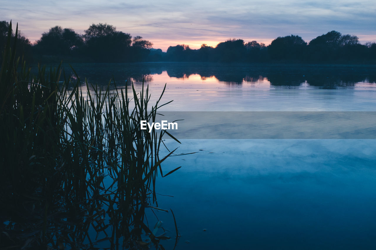 Scenic view of lake against sky at sunset