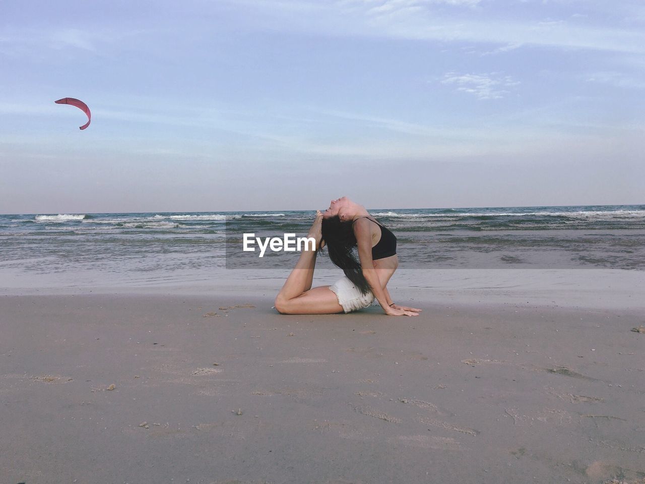 Woman exercising on beach against sky