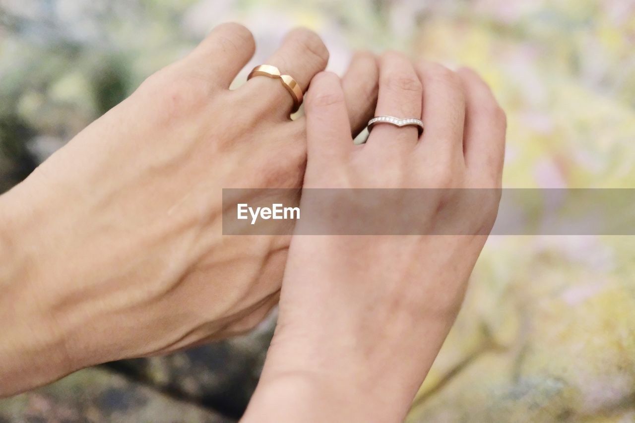 Cropped hands of couple wearing wedding rings outdoors