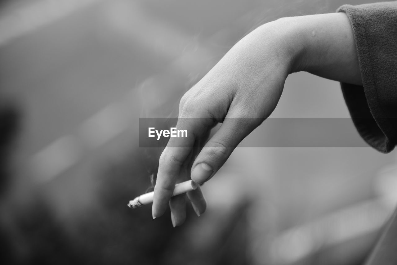 Close-up of hand holding cigarette 