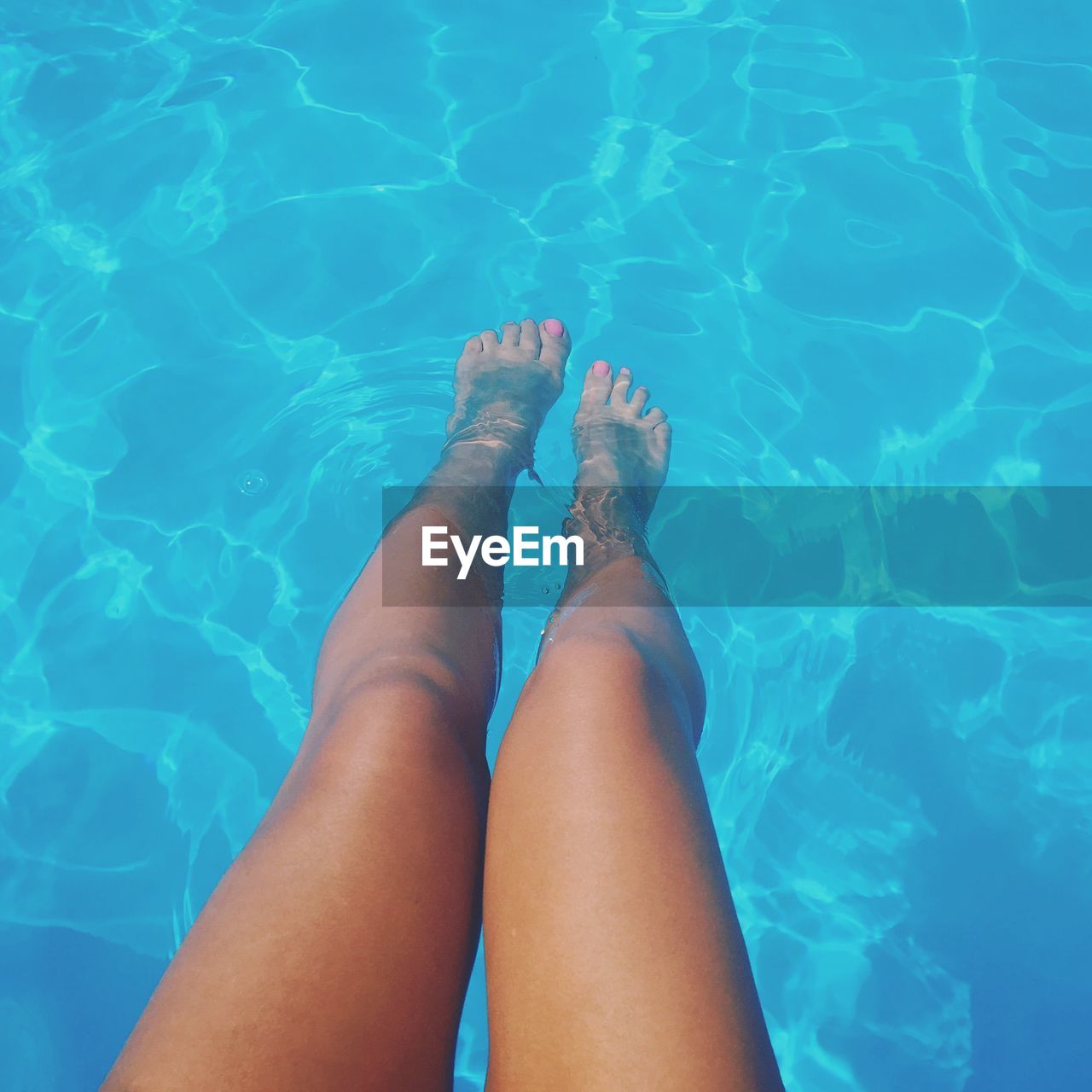 Low section of young woman relaxing in swimming pool