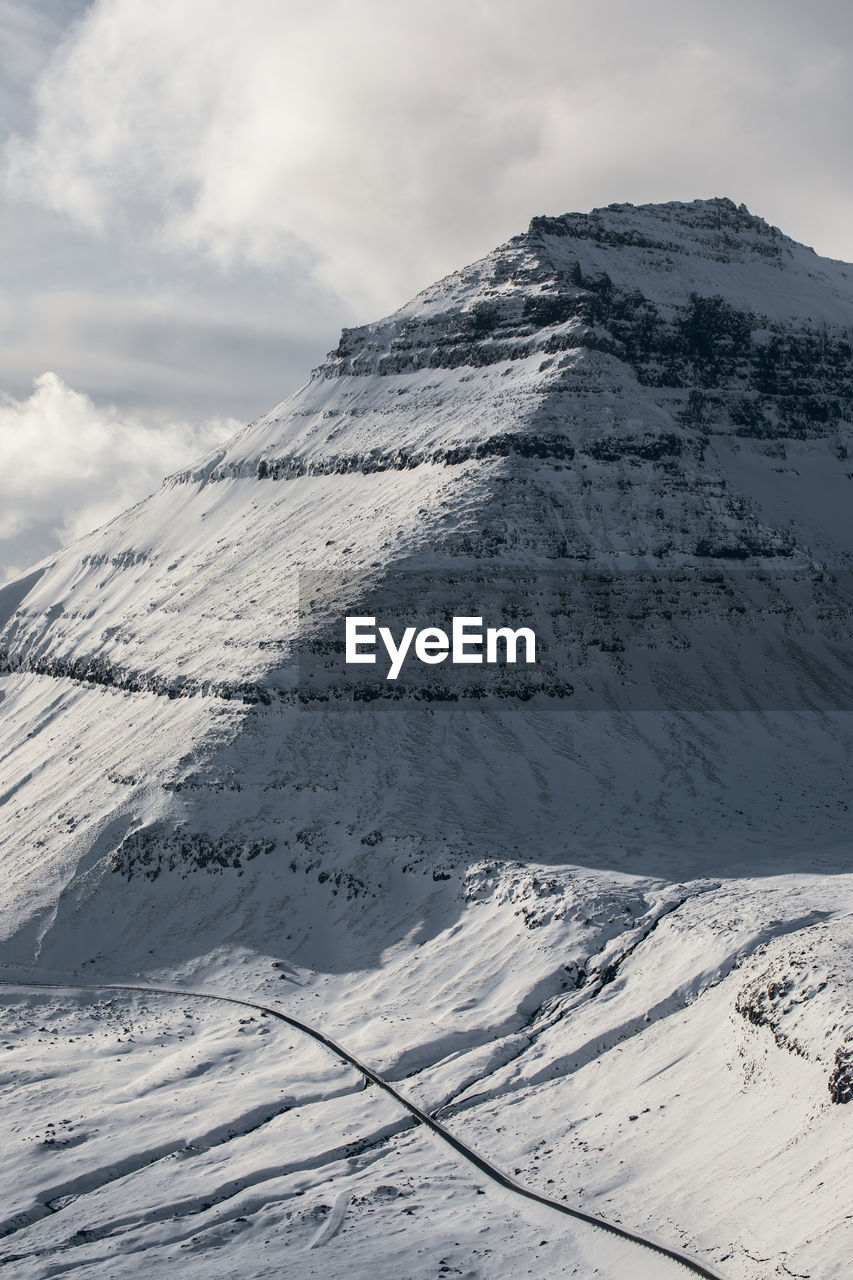 Picturesque view of mountainous terrain covered with white snow against gray sky on cold winter day in faroe iceland in iceland