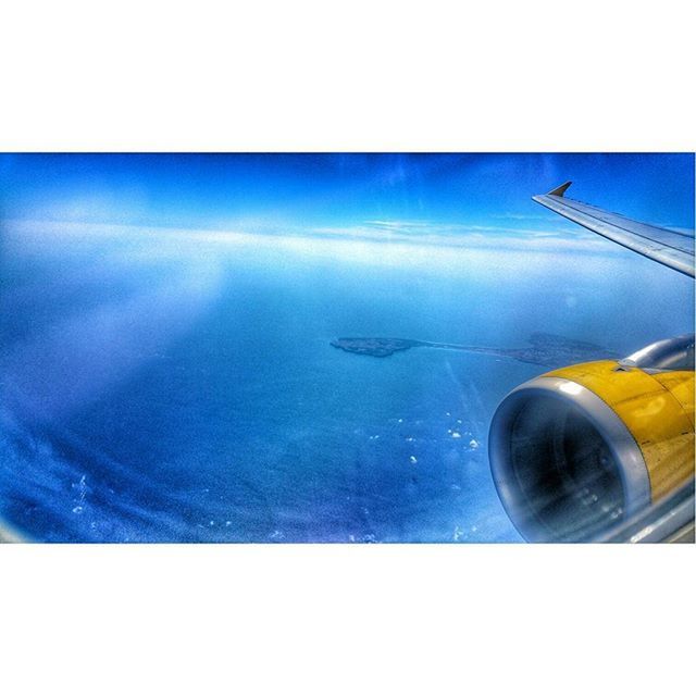 CROPPED IMAGE OF AIRPLANE WING OVER SEA