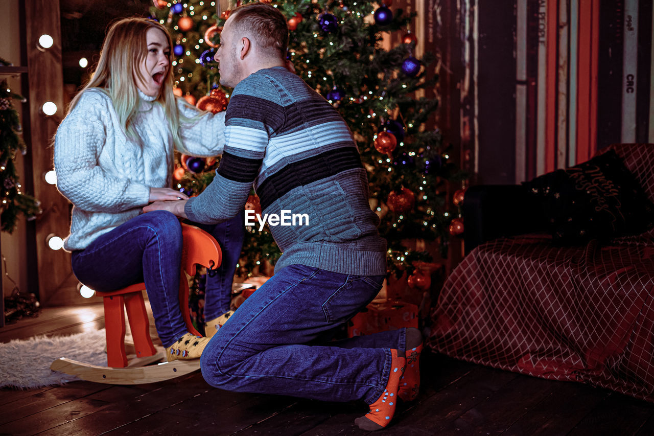 REAR VIEW OF TWO PEOPLE WALKING IN CHRISTMAS TREE