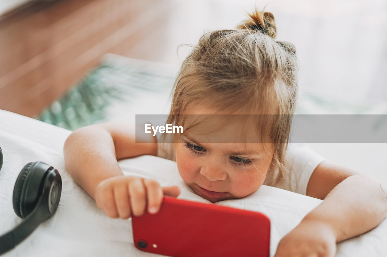 Close-up portrait of cute girl using laptop on bed at home