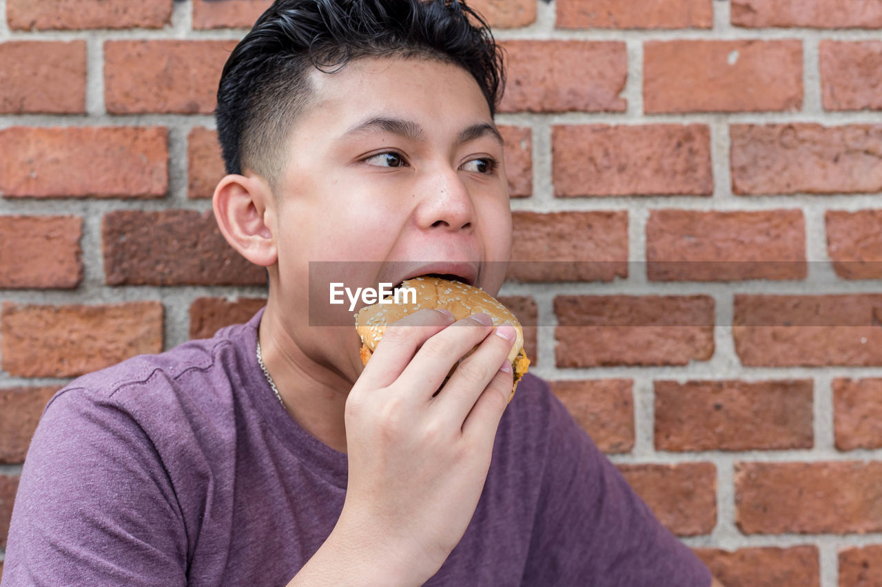 Young boy eating a hamburger.