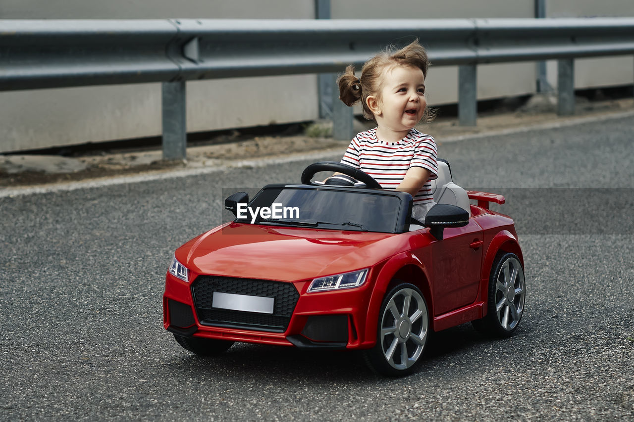 A girl riding a toy car