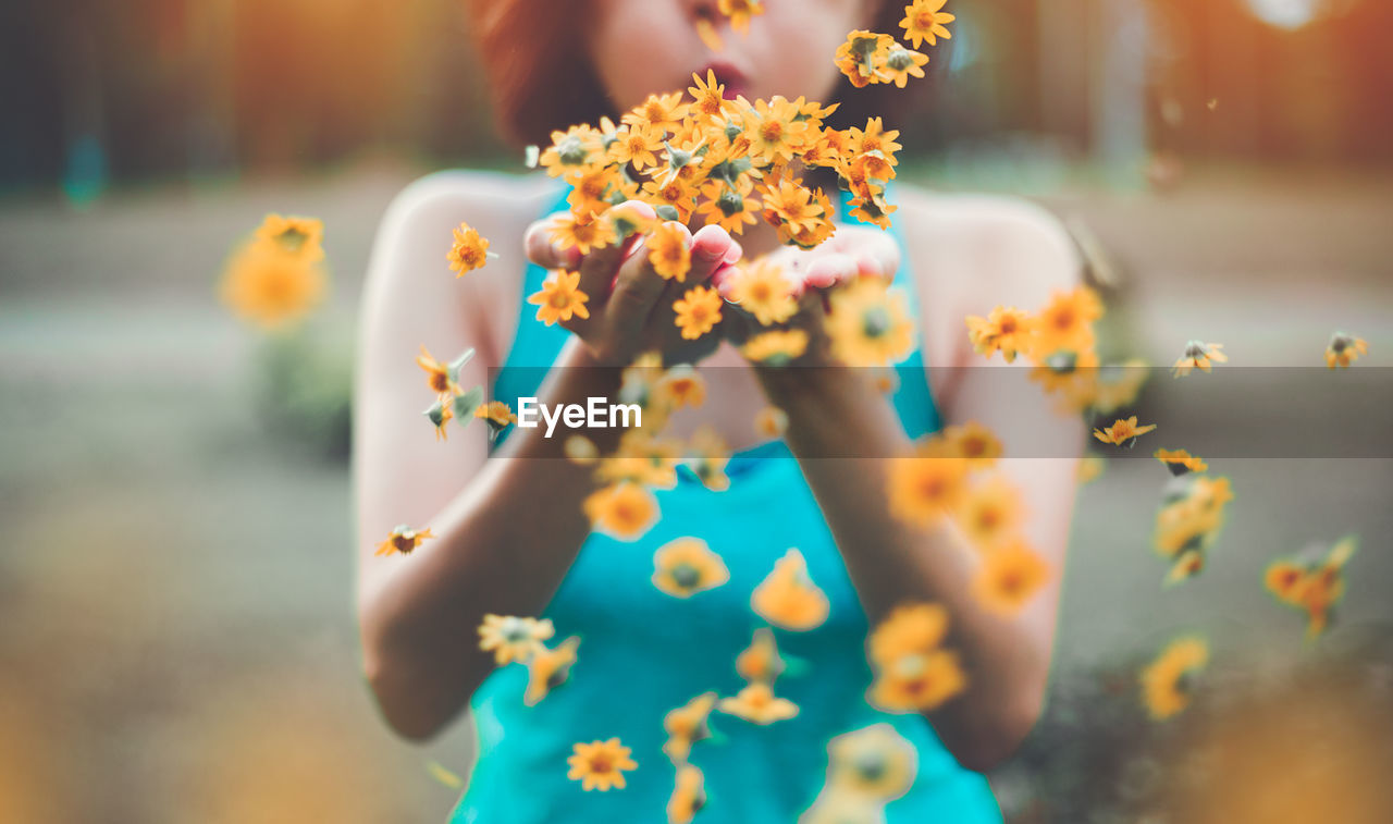 Midsection of woman blowing flowers