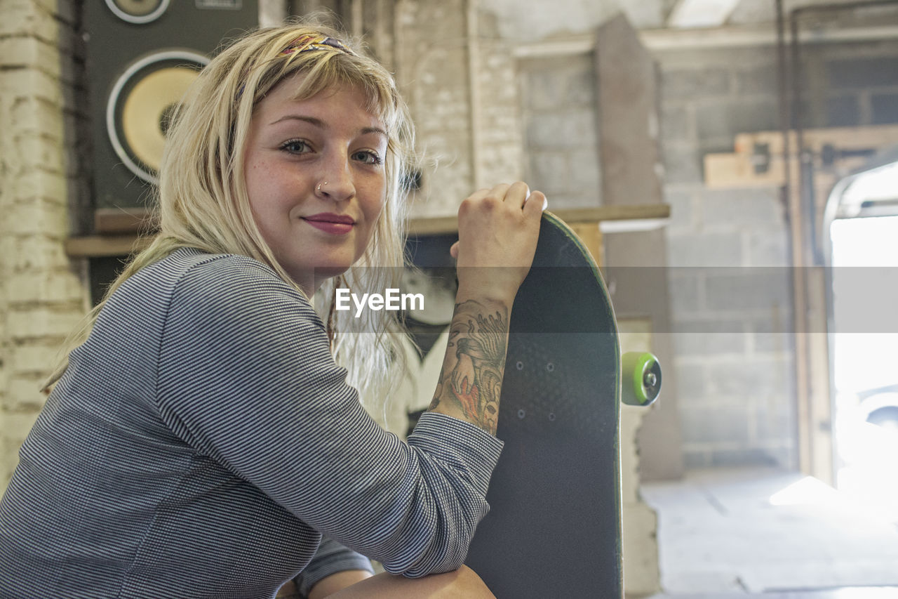 Young woman holding a skateboard.