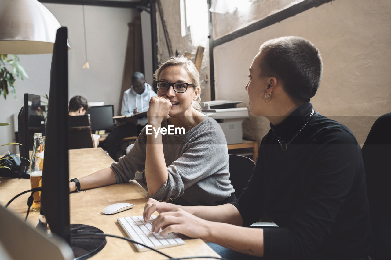 Businesswomen discussing while sitting at workplace