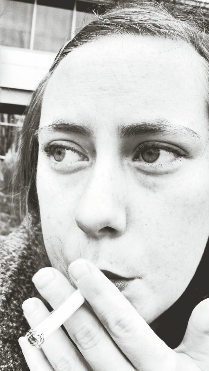 Close-up of thoughtful young woman smoking outdoors
