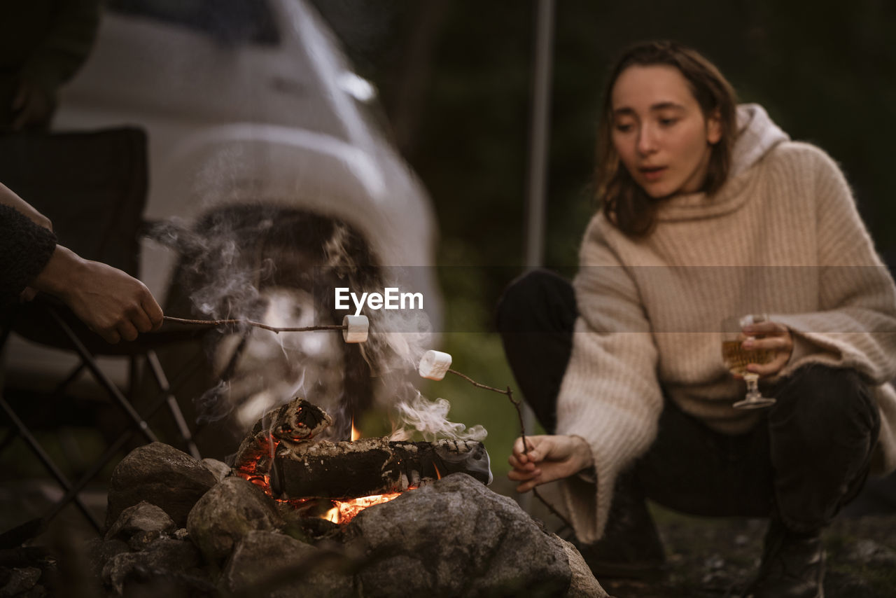 Woman roasting marshmallow over campfire