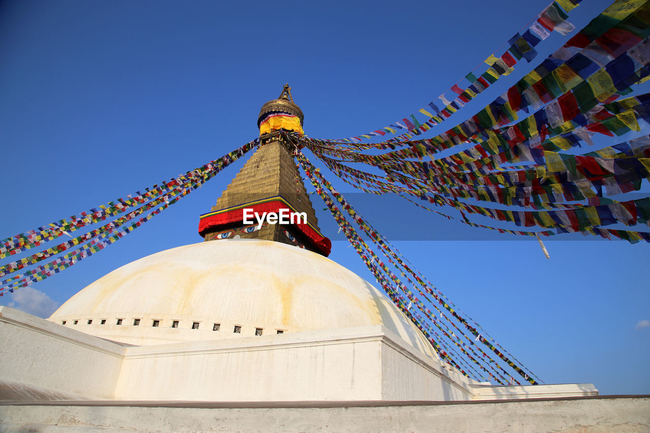 Low angle view of prayer flags on bodnath stupa against sky