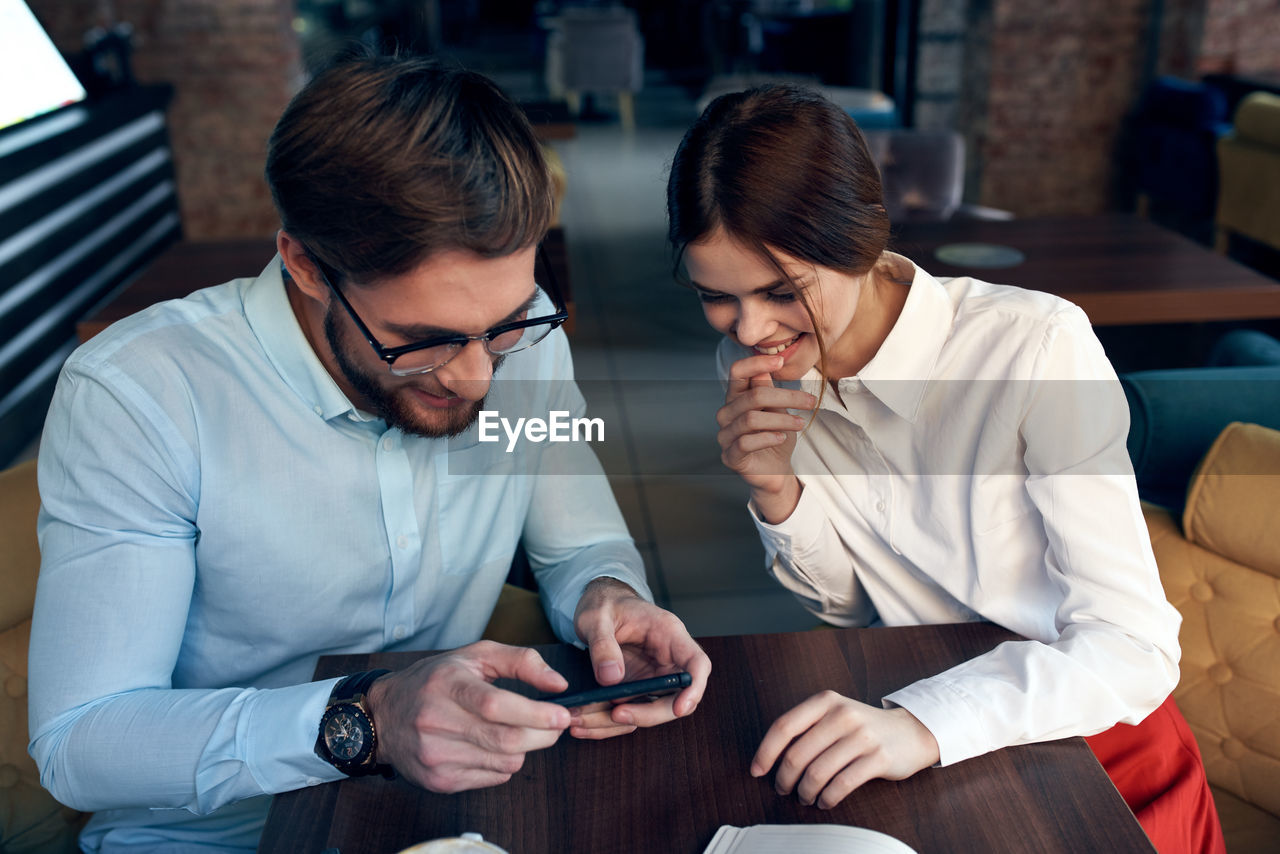 Cheerful colleagues looking at mobile phone